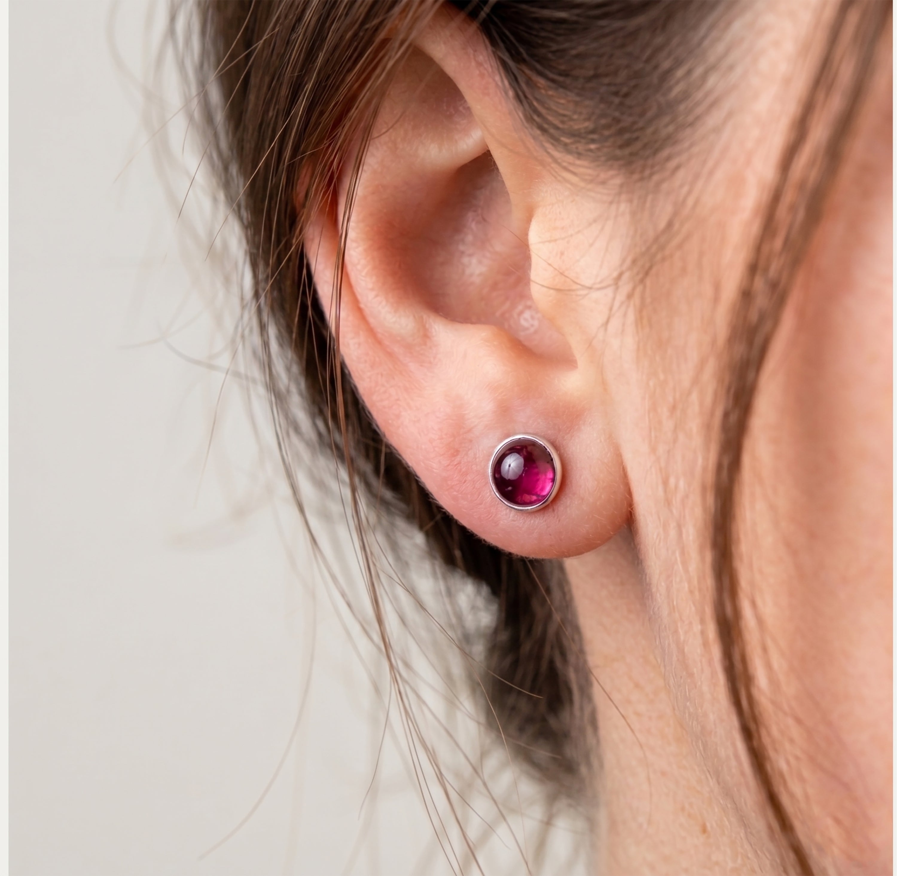 Model wearing Faris Jewels 8mm garnet stud earrings in sterling silver.