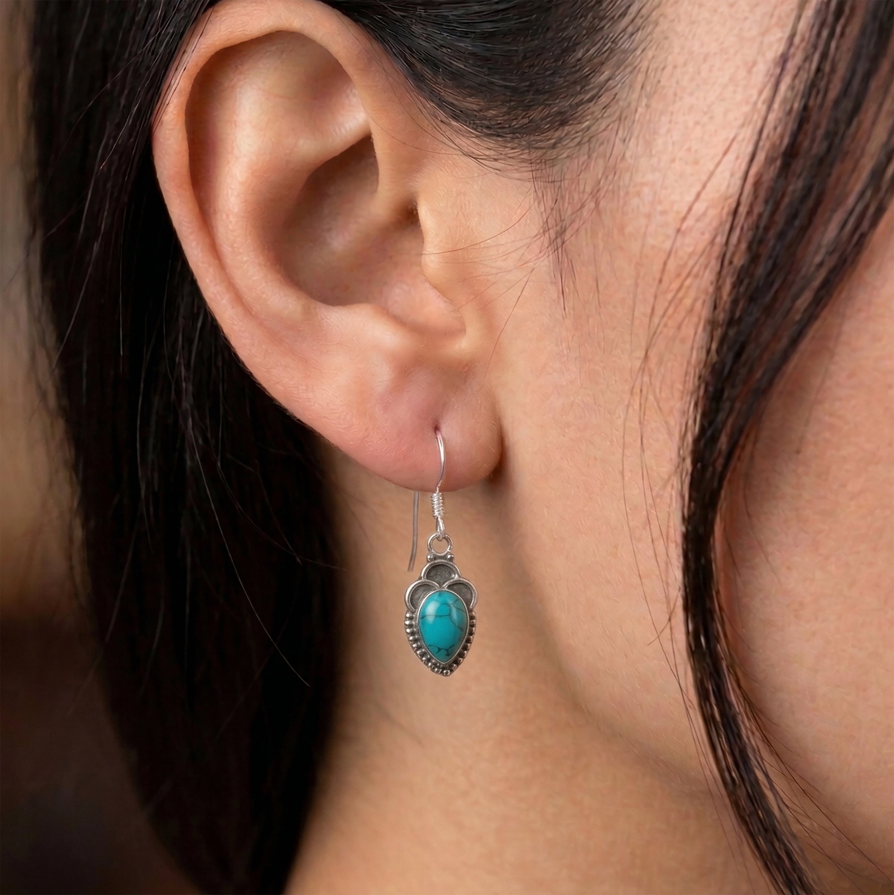 Model wearing Faris Jewels pear turquoise drop earrings in sterling silver to show 29mm length and scale