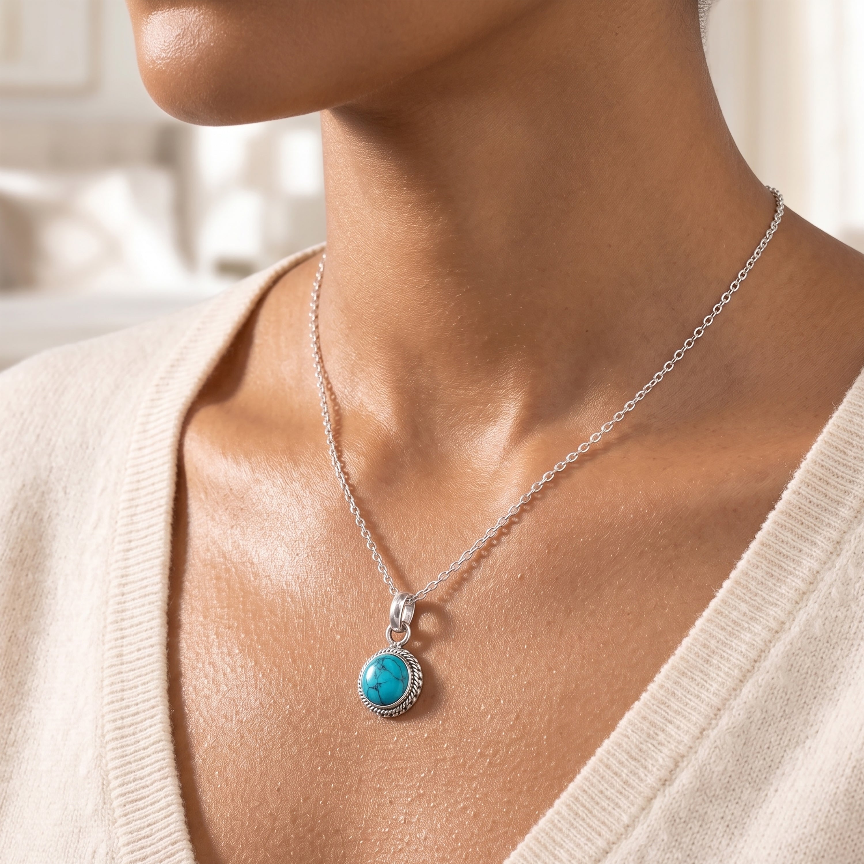 Close-up of a model wearing a dainty round turquoise pendant with a sterling silver rope-style border on a delicate silver chain